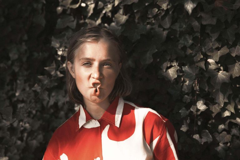 Fine-art portrait of a girl against a wall covered with ivy